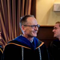 Male faculty member smiles as he waits for his award